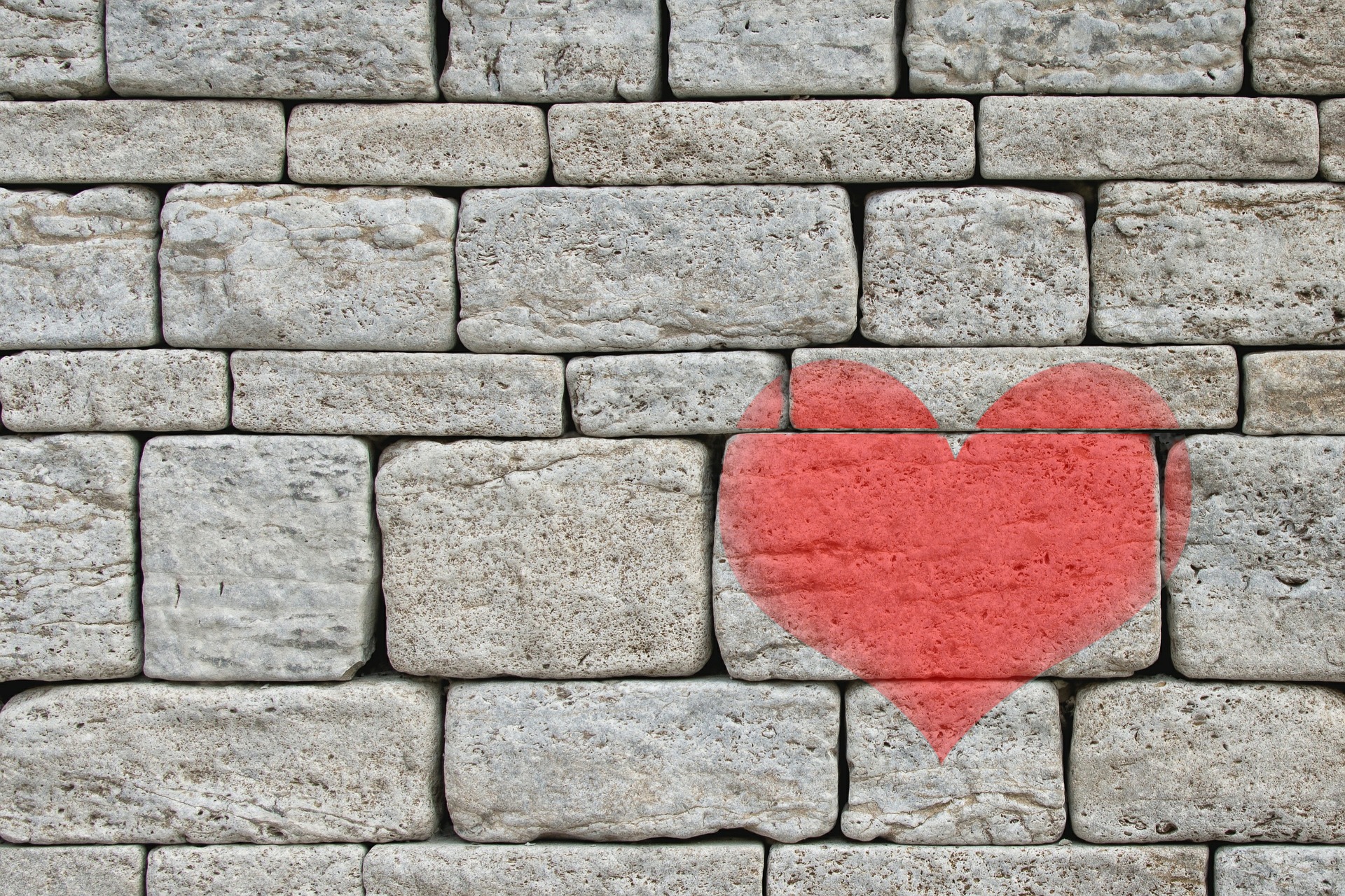 a stone faced brick wall with a red heart painted on it