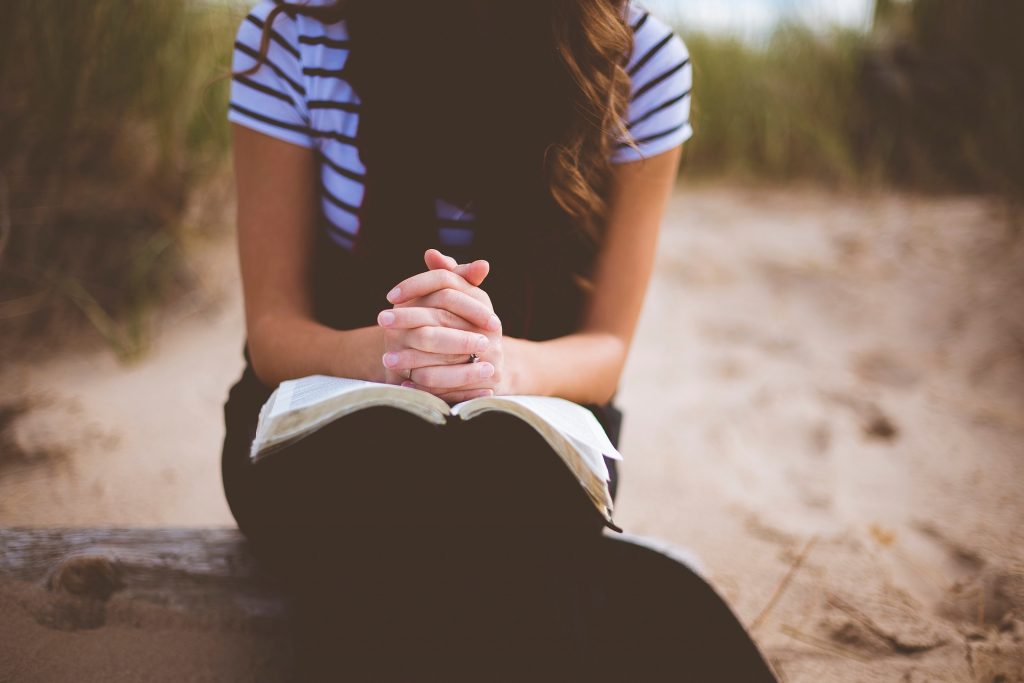 girl folded hands on Bible