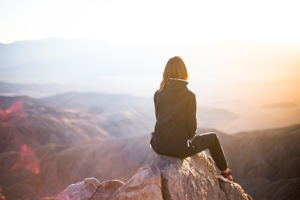 Woman sitting on top of mountain looking out over the landscape